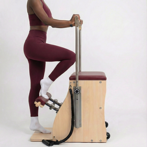 The Timber Chair by Oshun Studios: A solid wood split-pedal Pilates chair with black upholstery and adjustable handles.