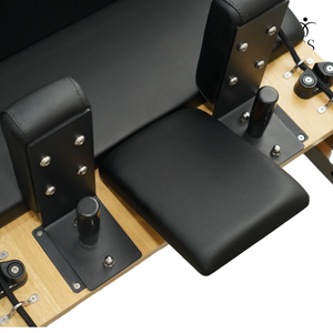 Close-up of the adjustable padded headrest and ergonomic shoulder blocks on the Timber Reformer carriage.