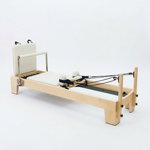Three-quarter angle of the Oshun Studios Timber Reformer in Maple with white upholstery and rope system