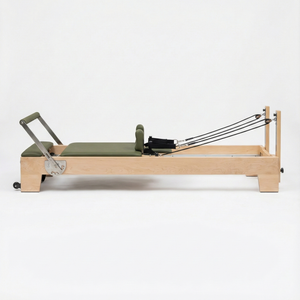Pilates reformer with green cushion on a white background