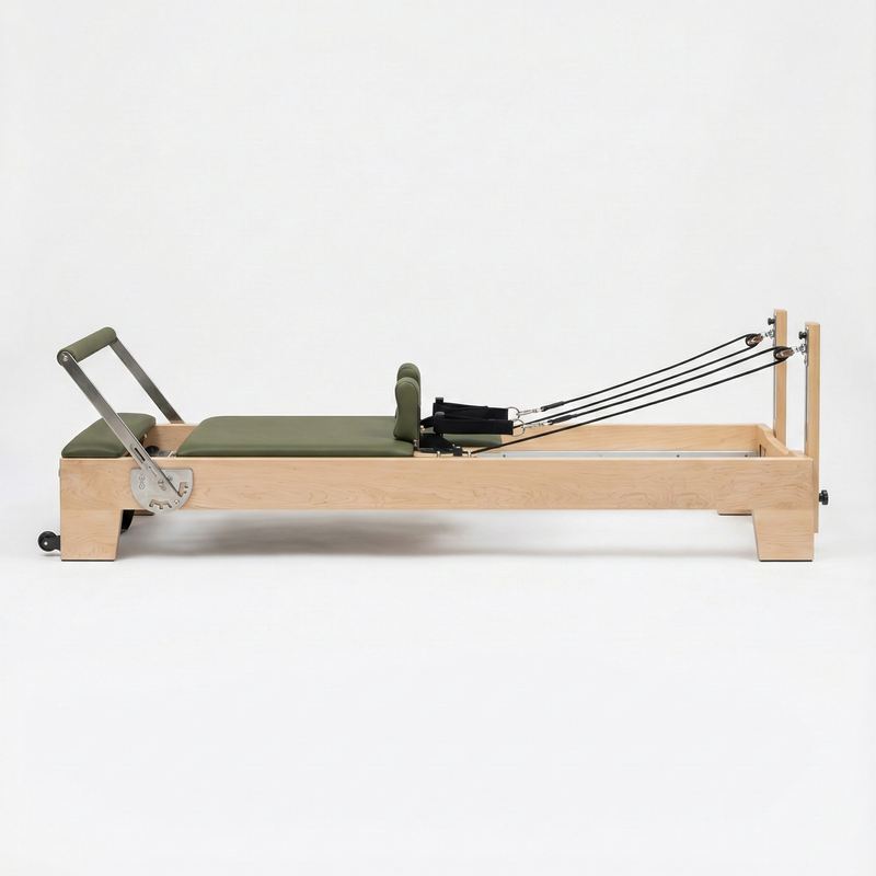 Pilates reformer with green cushion on a white background
