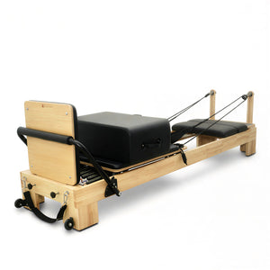 The Timber Reformer in solid oak shown with installed padded jumpboard and sitting box, configured for cardio and plyometric Pilates classes.