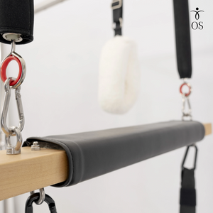 Padded Trapeze Swing bar featuring soft white wool "fuzzy" loops and red resistance springs on the Timber Cadillac Tower.