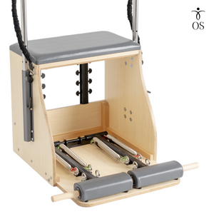 Pilates reformer machine with wooden frame and gray cushion on a white background