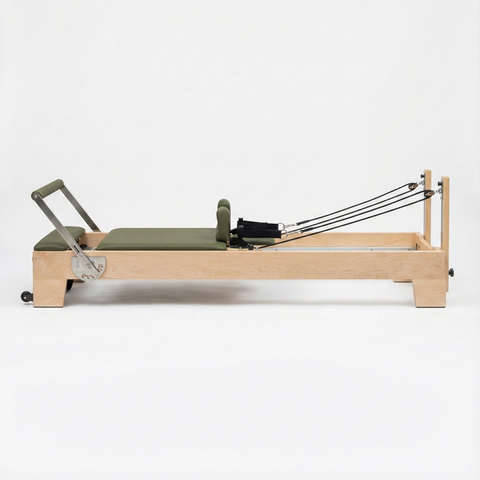 Pilates reformer with green cushion on a white background