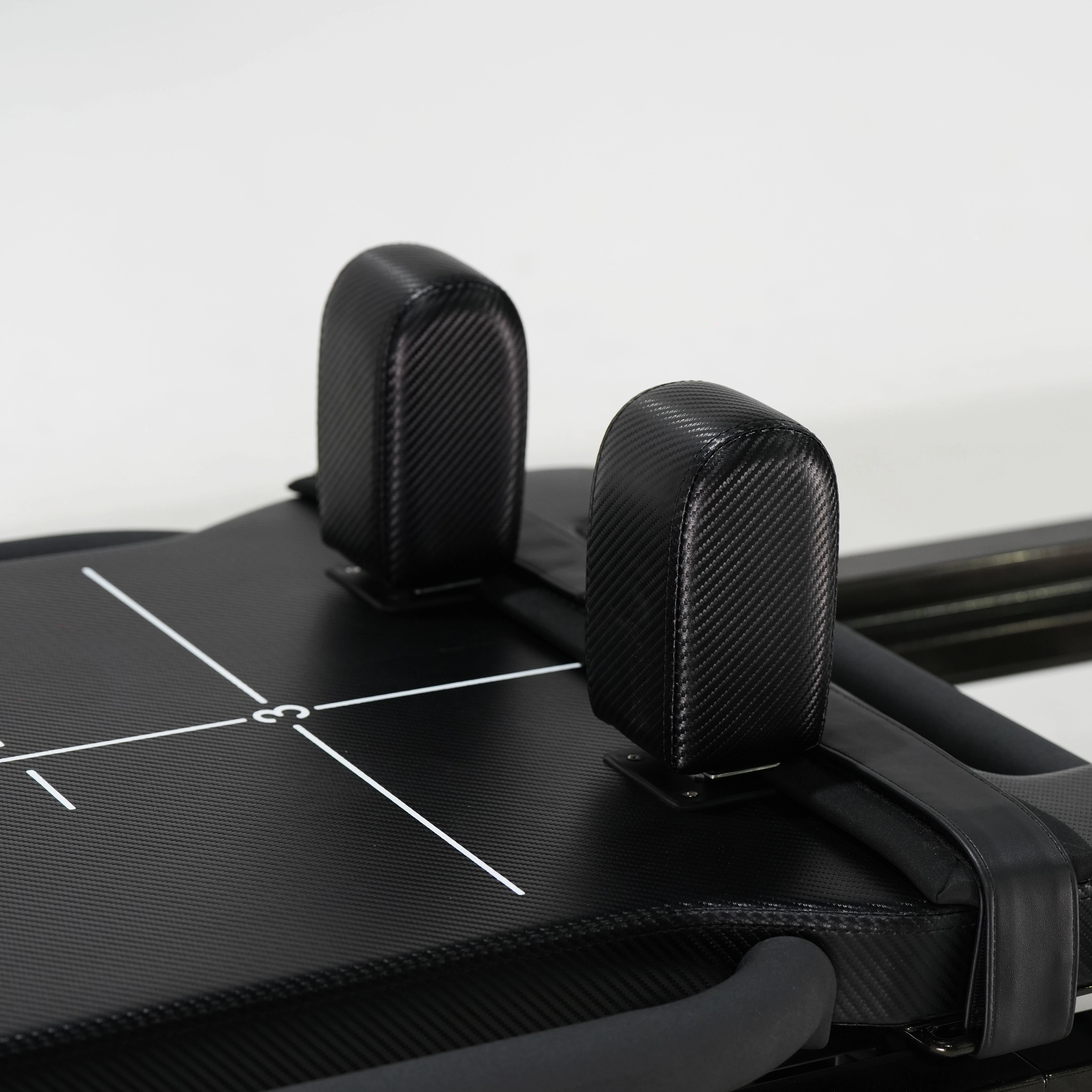 Padded adjustable headrest on the mega Reformer, shown in a raised position for neck support.