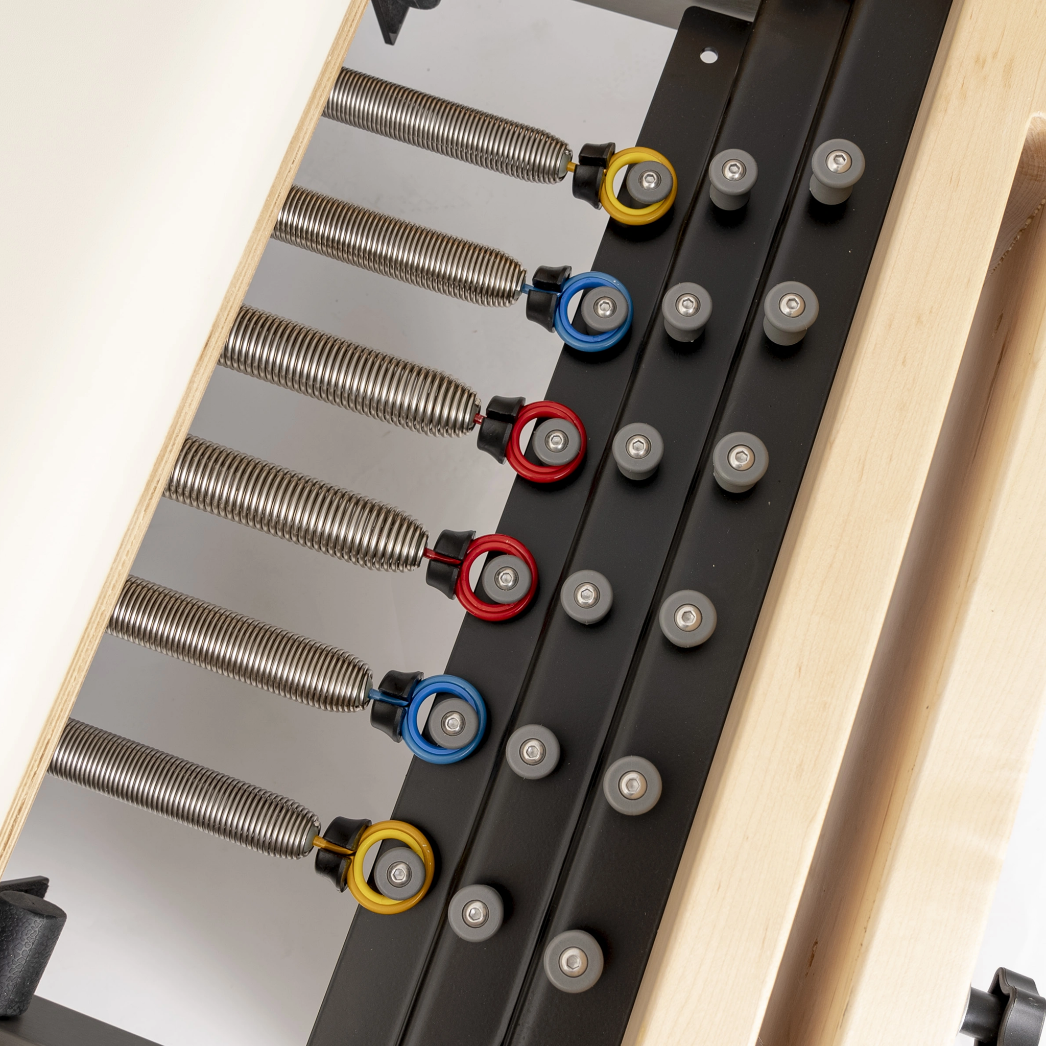 Close-up of the color-coded tension springs on the Maple Timber Reformer frame.