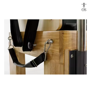 Adjustable black nylon foot strap attached to the solid Oak frame of the Timber Cadillac Reformer, designed to secure feet during Short Box exercises.