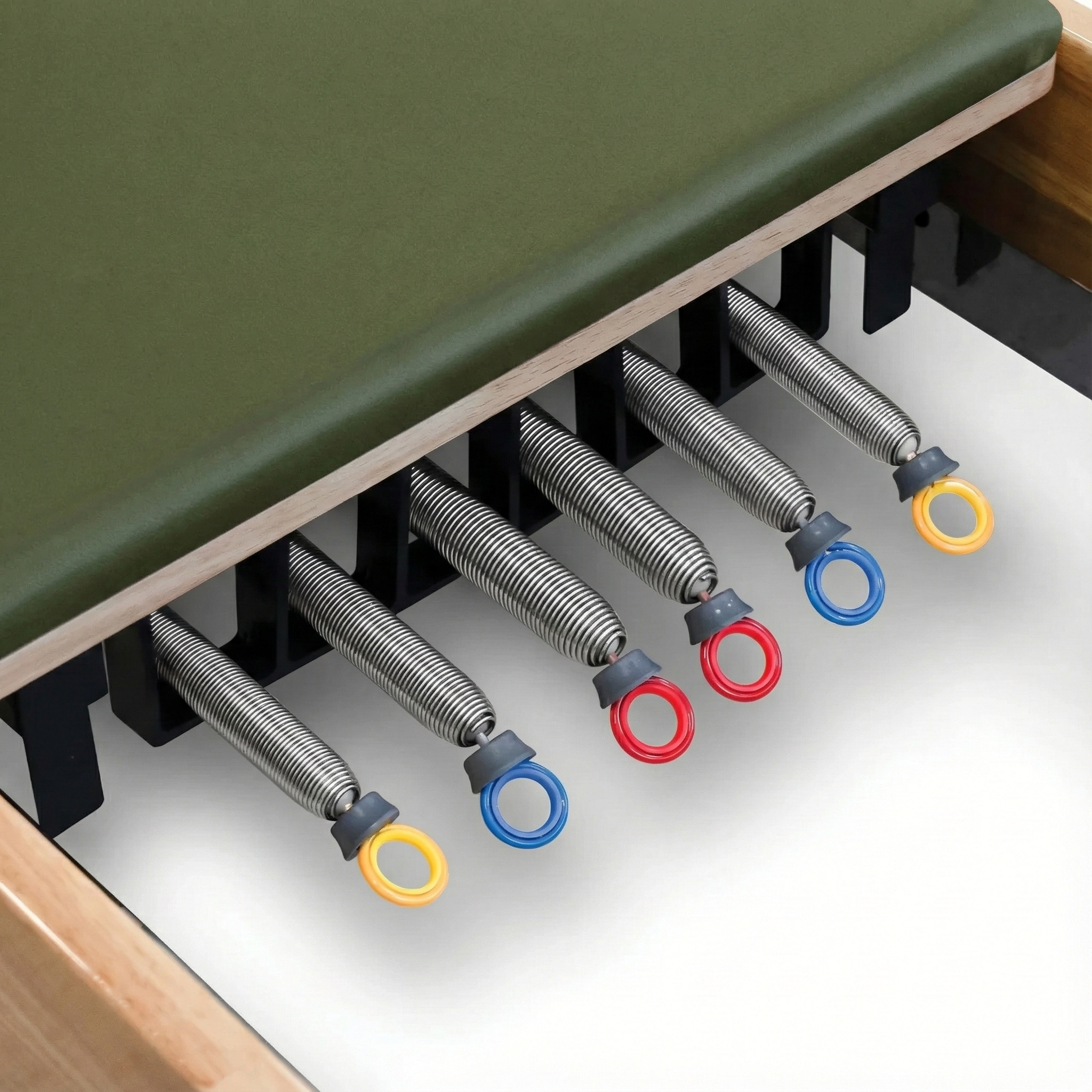 Close-up of the color-coded resistance springs attached to the solid Oak frame of the Timber Reformer by Oshun Studios.