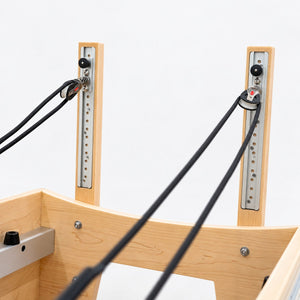 Height-adjustable rope pulleys on aluminum tracks in the maple risers of the Oshun Timber Therapy Reformer
