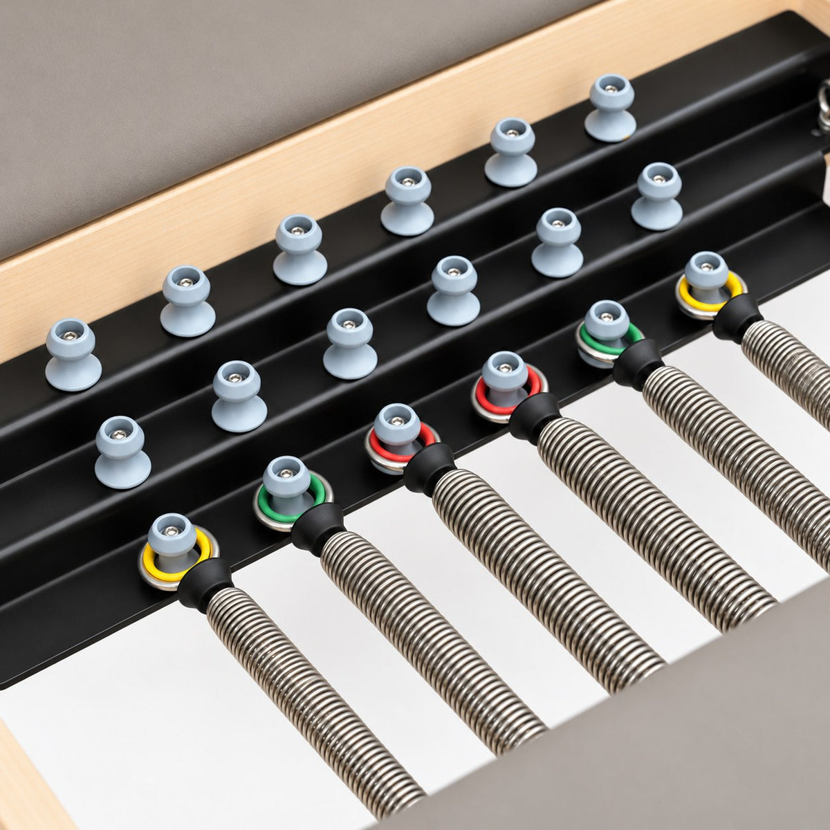Color-coded German springs on the spring bar of the Oshun Timber Therapy Reformer