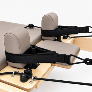 Taupe shoulder rests and black handle straps on the carriage of the Oshun Timber Therapy Reformer