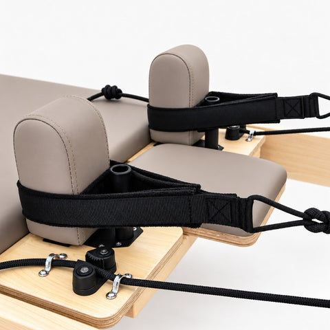 Taupe shoulder rests and black handle straps on the carriage of the Oshun Timber Therapy Reformer