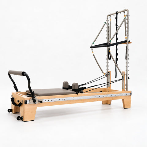 Oshun Timber Therapy Reformer Tower Edition in maple with taupe upholstery, a half tower and the sliding footbar on its aluminum side rail