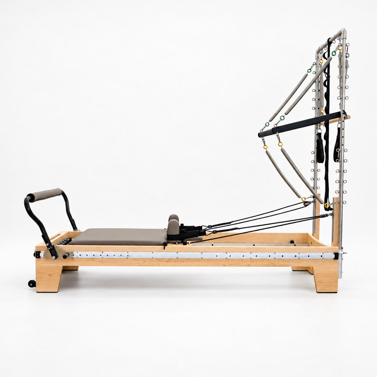 Side view of the Oshun Timber Therapy Reformer Tower Edition in maple, with the half tower, push-through bar and full-length footbar rail