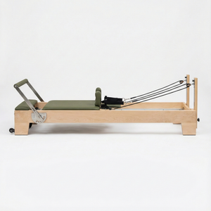 Oshun Timber Reformer in maple with olive green upholstery, side view on a white background