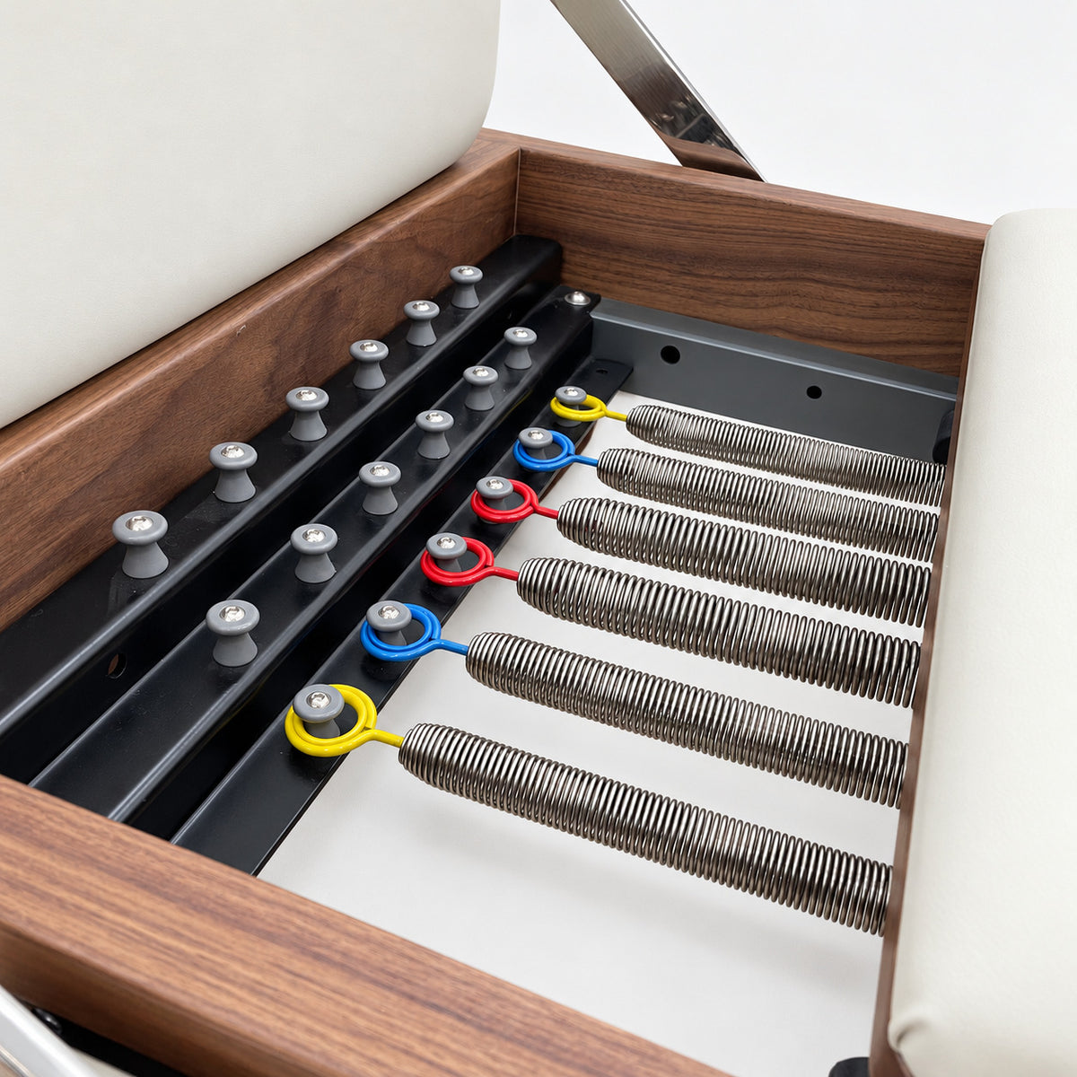 Six color-coded resistance springs on the spring bar inside the solid walnut frame of the Oshun Timber Reformer