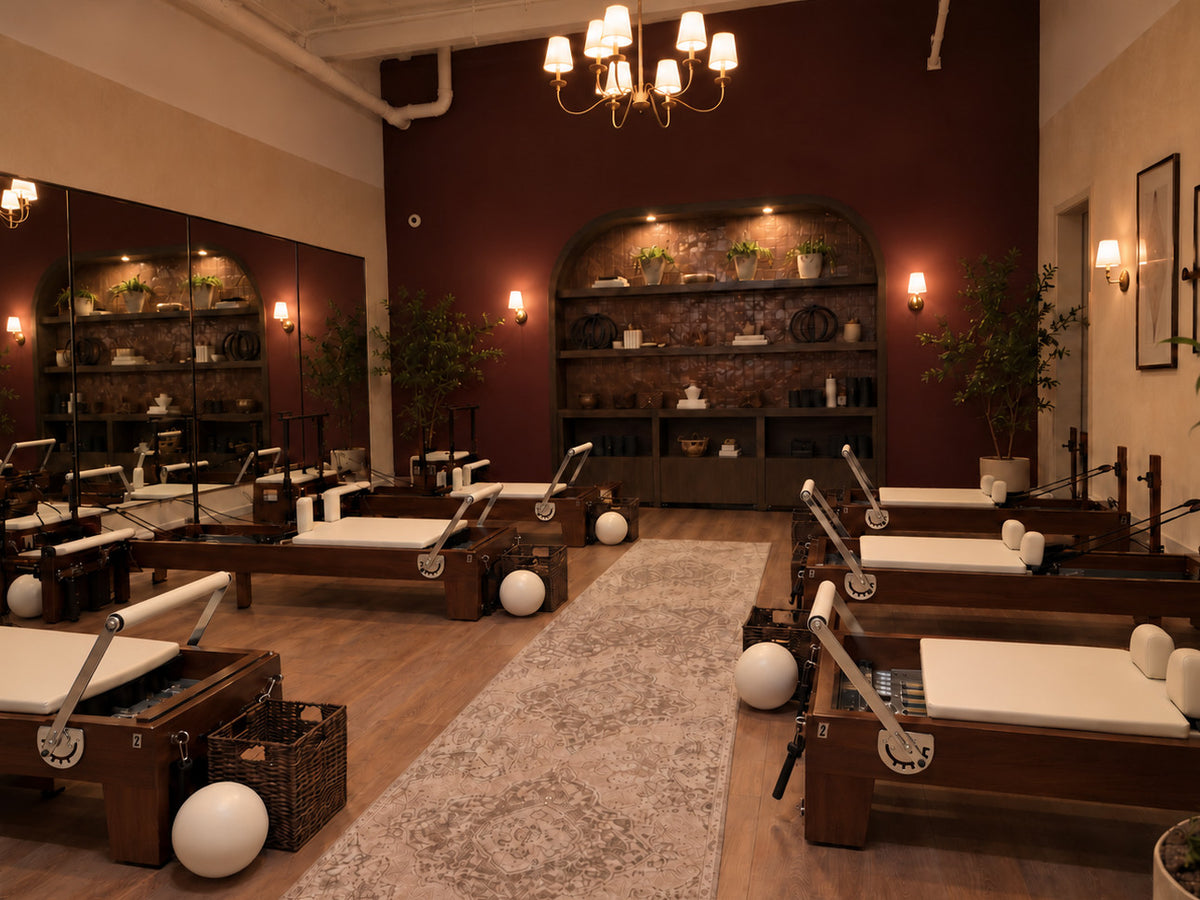 Solid walnut Oshun Timber Reformers with ivory upholstery in a boutique Pilates studio