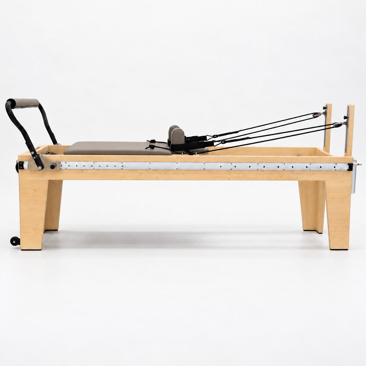 Side view of the Oshun Timber Therapy Reformer at Rehab Height, a 24 in maple frame on tall tapered legs, with the full-length footbar rail
