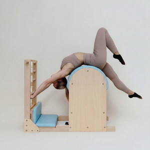 Person using a Pilates labber barrel against a white wall
